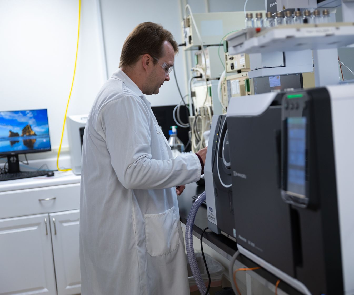 Scientist wearing white coat and eye protection analyzing a solution in lab