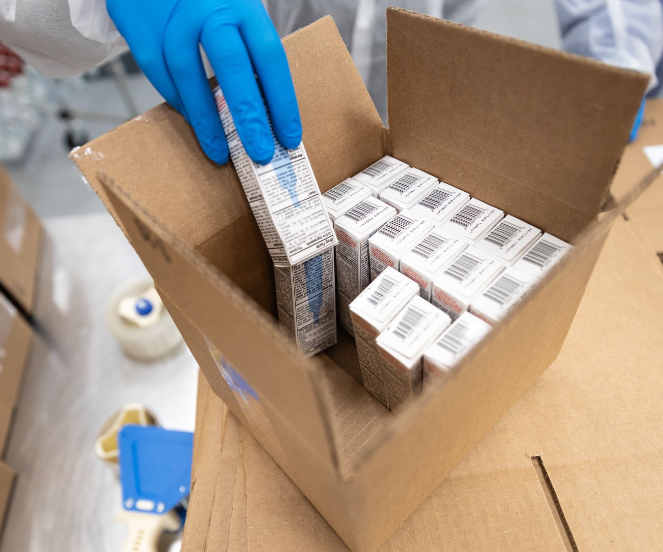 hand with blue glove loading finished products in to a box for packaging.