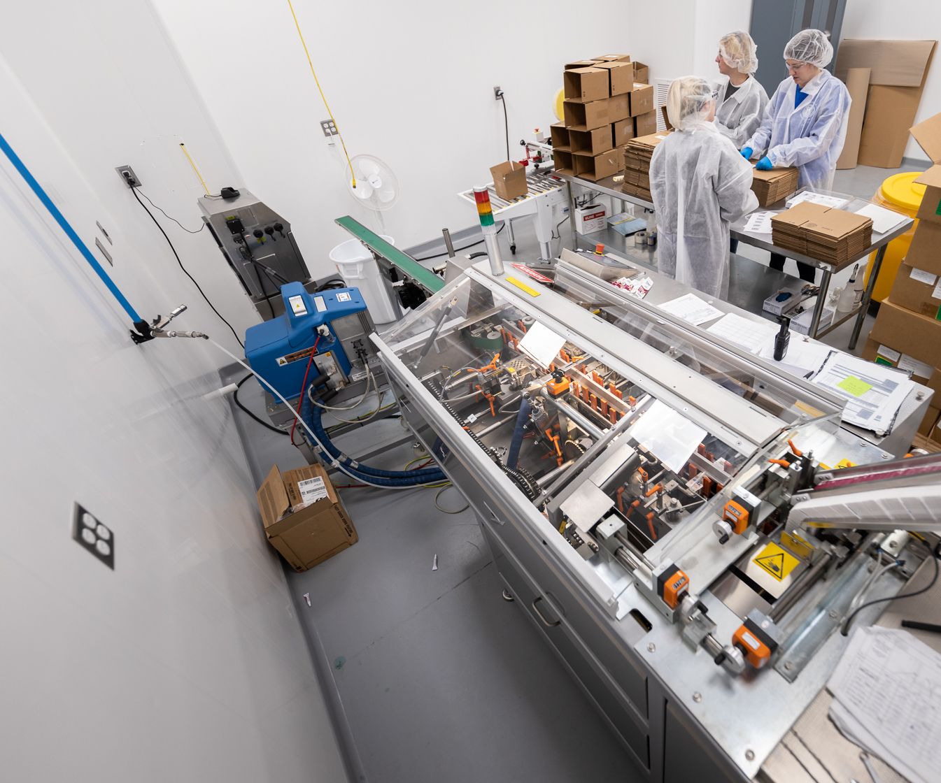 Lab workers in room with machine that packages products