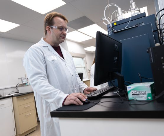 man with glasses and white coat using computer